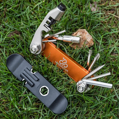 Portable Bicycle Repair Multi Tool With Chain Tool Torx Hex And Screwdriver For Road And Mountain Bikes Lightweight Compact On The Go Emergency Maintenance Kit In Bright Orange on grass