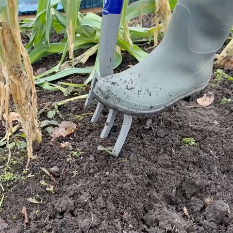 Neverbend Carbon Digging Fork For Heavy-Duty Yard Work in use, tilting soil with carbon steel head and Supergrip handle