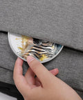 Hand placing Cute Zebra Watercolor Wireless Charger 10W Fast Charging Pad Slim Portable Charging Station into a gray bag pocket