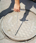 No Sweat Heavy Duty Manhole Cover Lift Hook With T Shaped Steel Puller For Drain Well Lid Opener and Roller Shutter Doors Rust Proof Stainless Steel Industrial Grabber Tool Top Shelf 43 Cm Grip in use lifting a manhole cover.