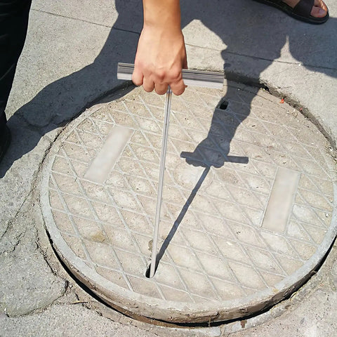 No Sweat Heavy Duty Manhole Cover Lift Hook With T Shaped Steel Puller For Drain Well Lid Opener and Roller Shutter Doors Rust Proof Stainless Steel Industrial Grabber Tool Top Shelf 43 Cm Grip in use lifting a manhole cover.