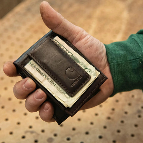 Premium Full Grain Leather Slim Bifold Wallet For Men In Rich Oil Tan Brown held in a hand with cash, showcasing its lightweight design.