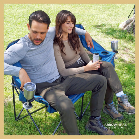 Couple sitting on Portable Folding Double Duo Camping Chair Loveseat For Two With Extra Cozy Padding And Wine Glass Holders