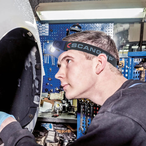 Person working in a workshop wearing Rechargeable COB LED Headlamp With Panoramic Beam Touchless On Off Sensor 400 Lumens