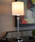 Camilla Steel And Acrylic Twist Buffet Lamp In Chrome And Clear Finish With Silver Faux Silk Shade on a sideboard in living space.
