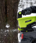 20-Volt Cordless Handheld Seed And Fertilizer Spreader For Yard Work in snow, gloved hand adjusting spreading rate dial