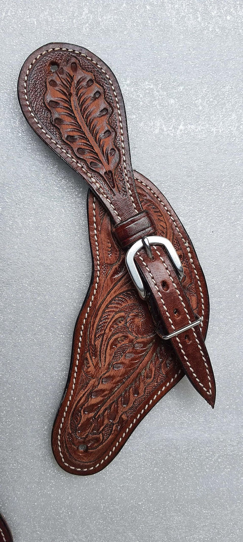 Oakleaf Tooled Leather Spur Straps For Adults with hardware and buckle, brown horse tack against a gray background