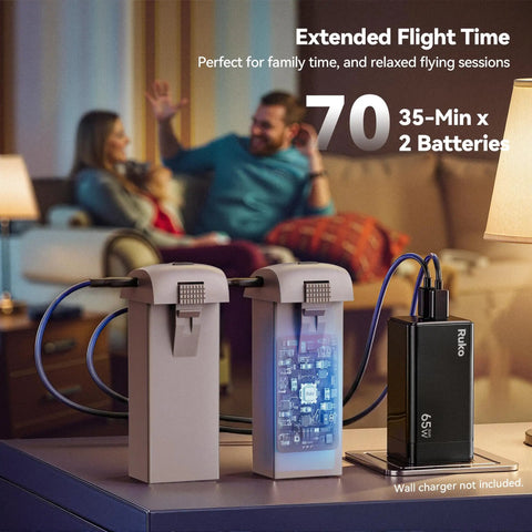 Two F11PRO 2 Drone batteries providing up to 70 minutes of flight, shown on a table with a charging setup, focus on battery details.