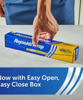 Person placing a hand on blue box of Nonstick Aluminum Foil Roll For Easy Cooking And Mess Free Cleanup Perfect For Covering Casseroles