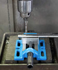 Pro Grade Cast Iron Drill Press Vise With 4 Inch Jaws mounted, securing round metal for precise drilling on heavy duty bench stands.