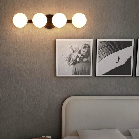 Sleek Matte Black Four Light Vanity Light Fixture With Opal Glass Globes, Modern wall sconce above artworks over bed