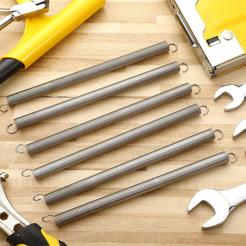 Front view: six 3/8 in x 6-1/2 in steel extension springs with dual-hook ends on a wooden workbench