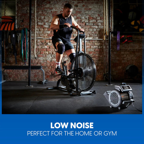 High Power Floor Fan With Remote Control 32 MPH Air Mover for home gym use, next to exercise bike in brick-walled gym