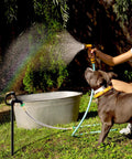 Person watering a dog using a 2-Foot Female To Female Garden Hose Connector With Metal Reel Adapter in a garden setting.