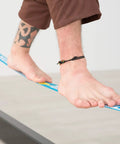 Feet balancing on Slackhouse 3.0 Indoor Slackline Structure Built For Gym And Home Training with 9.8 ft polyester webbing.