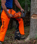 Man using chainsaw wearing Hi Vis Safety Orange Apron Style Chainsaw Chaps Type A Frontal Protection 5 Layer Chain Stopping Protective Fiber