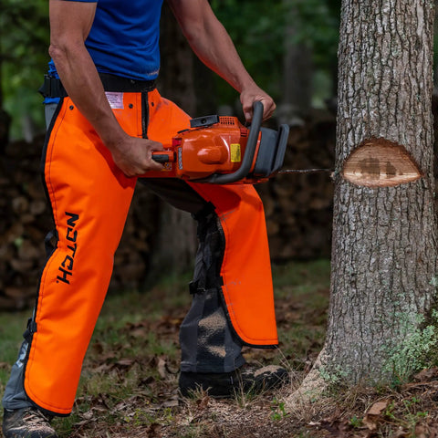 Man using chainsaw wearing Hi Vis Safety Orange Apron Style Chainsaw Chaps Type A Frontal Protection 5 Layer Chain Stopping Protective Fiber