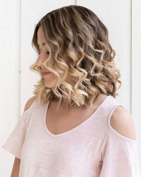 Woman with shoulder-length curly hair styled using the Slick Rotating Curling Iron With 0.75 Inch Ceramic Barrel Auto Rotation Dual Voltage