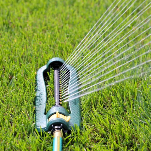 TurboTek Oscillating Sprinkler with 16 precision nozzles spraying water on grass, flexible tubing visible, green and yellow design