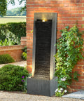 7-Tier Rock Water Fountain With Lights For Outdoor Garden Decor, Cascading Waterfall next to red brick wall