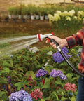 Person using Heavy Duty Garden Hose Nozzle With Five Adjustable Spray Patterns For Lawn And Garden Jet Shower Mist Sweep Fill
