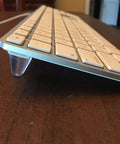 Side view of keyboard elevated by cone-shaped clear rubber bumper from 16 Piece Set Cone Shaped Clear Rubber Bumpers With Self Adhesive Tall Feet In 3 Sizes For Electronics, Computer Equipment, Audio Gear, Car Truck Accessories, Cutting Boards, Picture Frames, Cabinet Doors And More set.