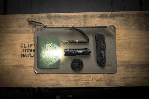 Dual Output LED Backup Flashlight With MaxVision Beam Technology on a tray with EDC items, showing compact rugged design for tactical use.