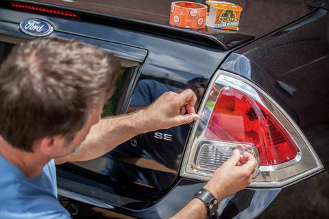 Man applying Crystal Clear Duct Tape 1.88 Inch by 9 Yard Heavy Duty All Purpose Tape Weatherproof Clear Repair Tape on car tail light