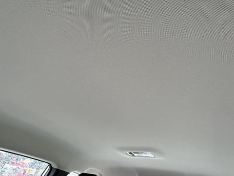 Auto headliner fabric mesh, light gray, foam-backed interior roof, installed in a vehicle with overhead light.
