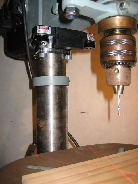 Drill Press Laser Crosshair Guide For Precise Drilling In Your Shop installed on benchtop drill press showing red crosshair.