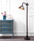 Dragonfly Tiffany-Style 60-Inch Arched LED Floor Lamp in Bronze next to a blue dresser, lit up with energy-saving LED bulbs included.