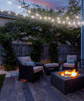 Outdoor patio at dusk with fire pit, cozy wicker chairs, and string lights under a sky, creating a relaxing atmosphere.