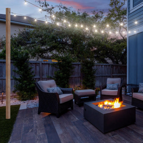 Outdoor patio at dusk with fire pit, cozy wicker chairs, and string lights under a sky, creating a relaxing atmosphere.