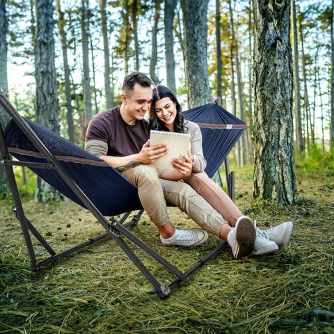 Couple relaxing on a Two Person Hammock With Stand Foldable Outdoor Hammock Set 600 Lb Capacity in a forest setting