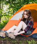 Person outside an orange tent using Seam Grip WP Waterproof Sealant And Adhesive For Jackets Tents Tarps Rain Gear And Outdoor Fabric.
