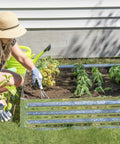 Woman gardening with a galvanized steel raised garden bed for flowers and plants, easy access design for better drainage, 40 by 40 inch size.