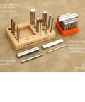Steel 2.5 Inch Swage Block With 16 Punch Set for jewelry making on wood stand and rubber base, shown organized on a table.
