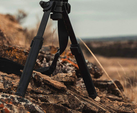 Rifle Bipod Gun Rest For Hunting And Target Shooting, MLOK Compatible, Ultralight Mil Spec Aluminum With Durable Polymer Feet on rocky terrain.