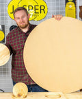 Man holding large and small wooden circles cut with Circle Cutting Router Jig With Pro Grade Precision For Making Perfect Circles From Two And A Quarter Inches To Eighteen And One Sixteenth Inches In One Sixteenth Inch Increments 256 Circle Sizes Industrial Grade Polycarbonate Lifetime Guarantee