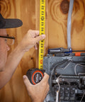 Person measuring wall with One And Three Sixteenths Inch By Sixteen Foot Tape Measure With Yellow Clad Command Control Anti Pinch Tip.