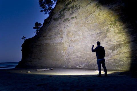 Person using 650 Lumen LED Flashlight With Slide Focus And Beam Lock Pure Beam Focusing Optics For Spot To Flood Control on beach