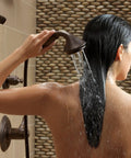 Woman using Cassidy Single Lever Bath Diverter and Transfer Valve Handle Kit in Venetian Bronze for shower, back view.