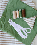 Cordless Electric Scissors For Fabric Cutting on green fabric with spools of thread and a striped fabric triangle.