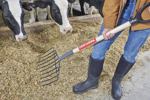 Person using Manure Fork With 30 Inch Hardwood Handle For Moving Manure Mulch Hay And Loose Materials, Heavy Duty 10 Tine Fork, One And A Half Inch Tine Spacing, Welded Tines For Longevity, Comfortable Grip For Yard Work And Easy Cleanup.
