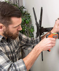 Man installing TV mount on wall using SnapToggle Be Toggle Anchor Zinc Plated Steel Channel For 3/8 To 2-1/2 Grip Range In Hollow Walls For 5/16-18 UNC Fasteners Pack Of 25 With Easy One Person Installation Behind Gypsum Board Drywall Concrete Block Ideal For Secure Mounting In Residential.