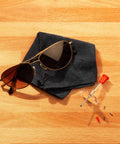 Eyeglass Repair Tool Kit With Small Screwdriver, Spare Screws, Magnifying Glass, Screw Guide, And Universal Storage Pouch For Quick Fixes To Reading Glasses And Sunglasses On The Go displayed with sunglasses on a cloth