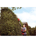 Person using Cordless Pole Hedge Trimmer With 18 Inch Dual Action Blades, 180 Degree Pivoting Head For 5 Cutting Angles, 11 Foot Reach.