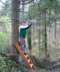 Child using Backyard Zip Line Kit With 100 Foot Cable And Trolley Heavy Duty 350 Lb Capacity Aluminum Handle in forest