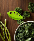 Zero Stress Leaf Stripper For Fresh Kale And Collard Greens With Super Sharp Curved Cutting Edge Quick Herb Chopper Kitchen Gadget on wooden surface with kale and stems.