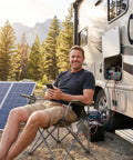 Man using 12V 20A PWM Solar Charge Controller with Type C USB Output, connected to RV setup in outdoor off-grid environment.
